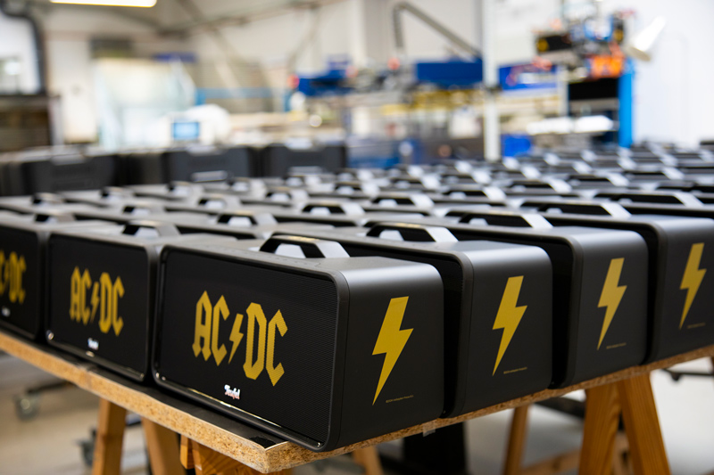 BOOMSTER AC/DC Edition Lautsprecher in der Druckerei Union-Klischee, mit goldenen AC/DC Logos auf der Frontseite und Blitzsymbolen auf den Seiten.